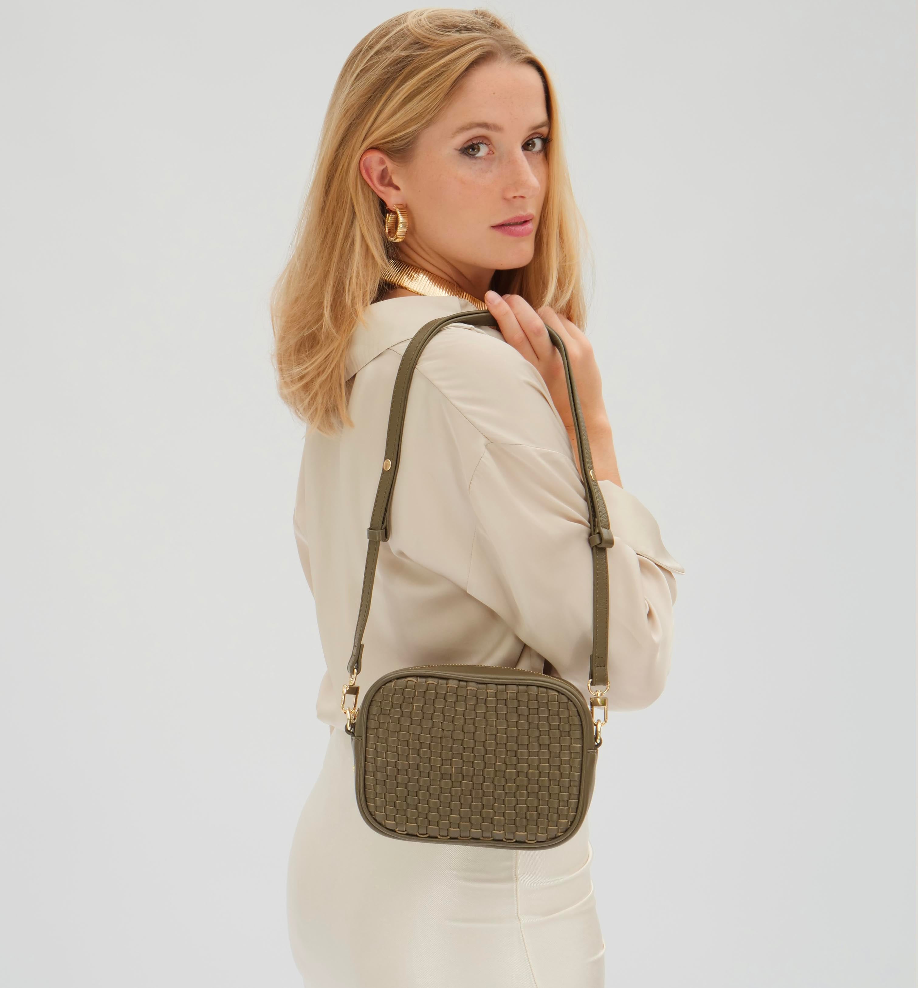Woman wearing a beige shirt with a green woven handbag on a white background